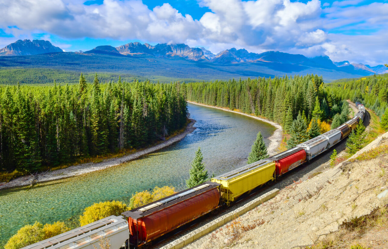 Long Freight Comtainer Train Moving Along Bow River In Canadian